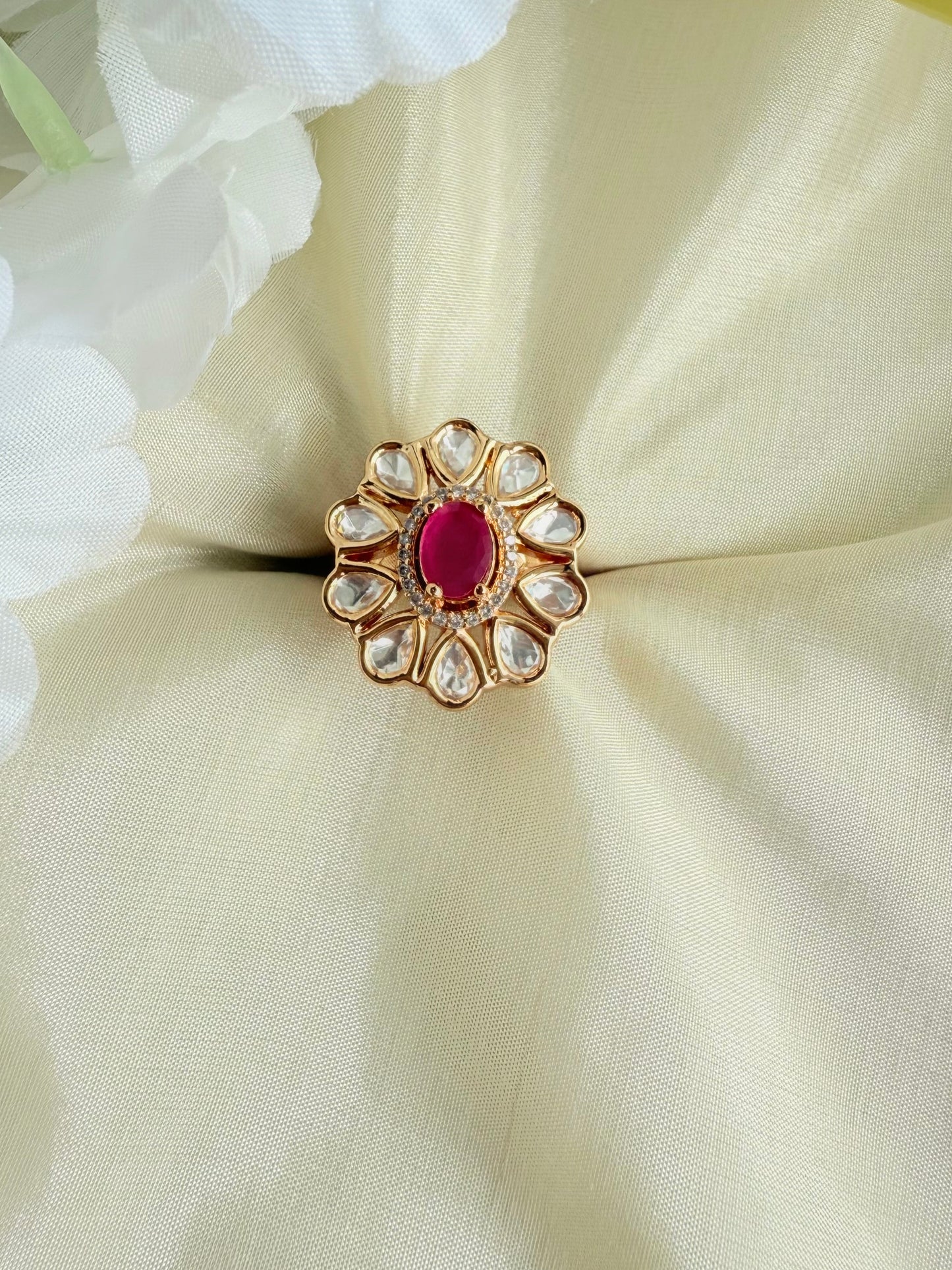 Gold ring with a red gemstone on a white fabric background