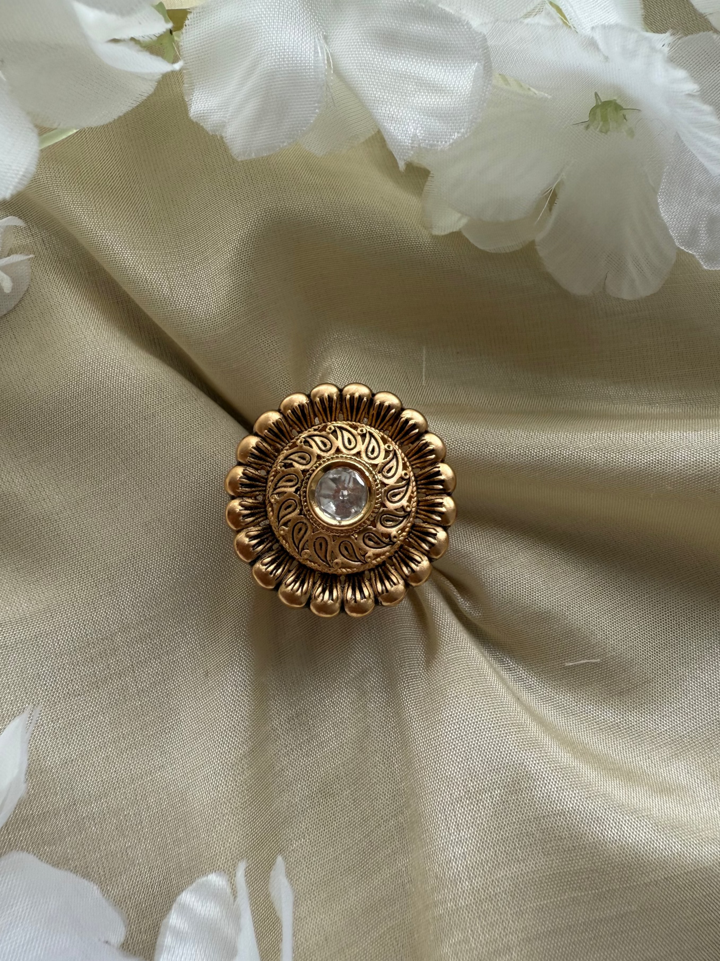 Gold decorative button on beige fabric with white flowers