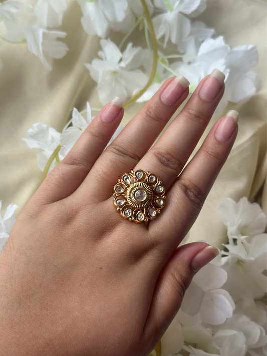 Hand wearing a gold ring with a floral background
